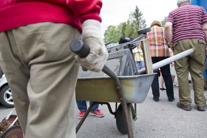 Henkilö kantaa kottikärryillä tavaraa.