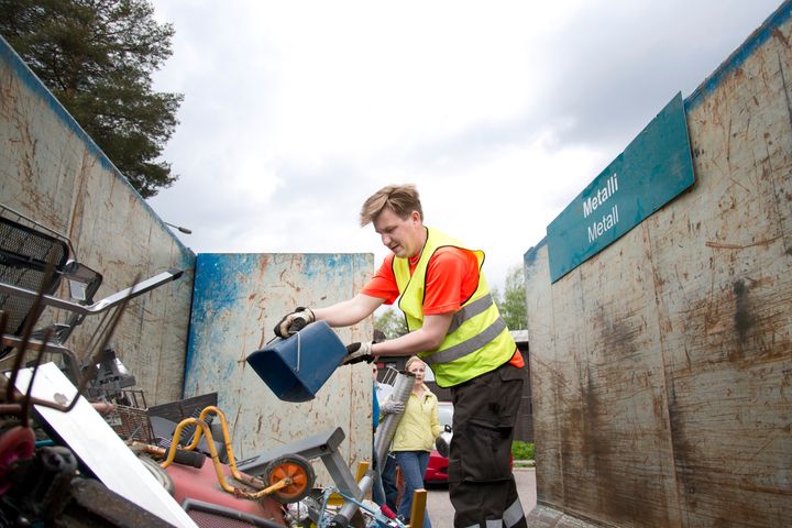 Henkilö tyhjentää jäteastiaa Sortti-keräyskierroksen lavalle.