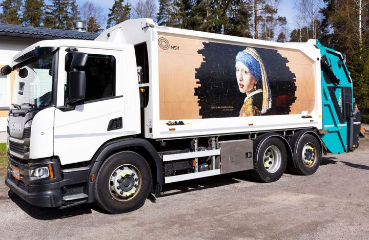 Taidejäteauto "Tyttö ja kartonkikorvakoru" kuvattuna pihalla.