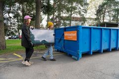 Kaksi asukasta kantaa taulutelevisiota Sortti-keräysautokierroksen sähkölaiteromulavalle.