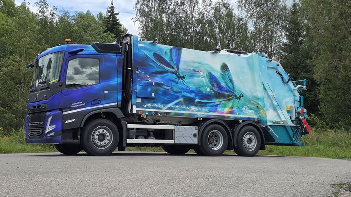 HSY:n taidejäteauton kyljessä liitää neidonkorento virtaavan veden yllä.