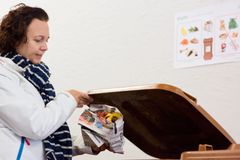 Henkilö laittaa sanomalehdestä taitetun biojätepussin ruskeaan jäteastiaan.