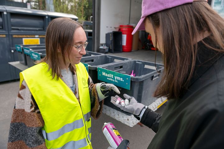 Sortti-keräysautokierroksen työntekijä auttaa asukasta vaarallisten jätteiden lajittelussa.