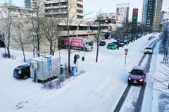 Harmaa mittausasema seisoo kadun varressa.