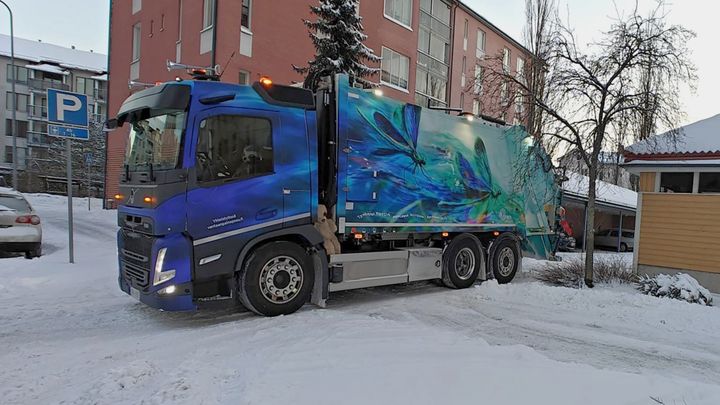 HSY:n jäteauto on pysähtyneenä kerrostalon jätetilan edessä.