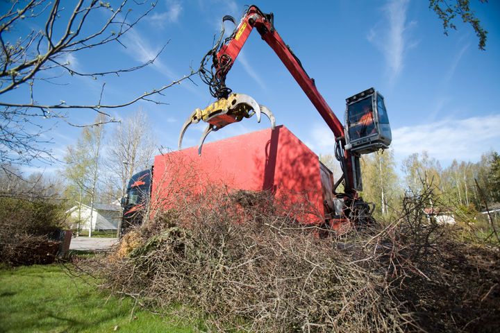 Kuorma-auto kuormaa piha-alueelle kerättyä risukasaa.