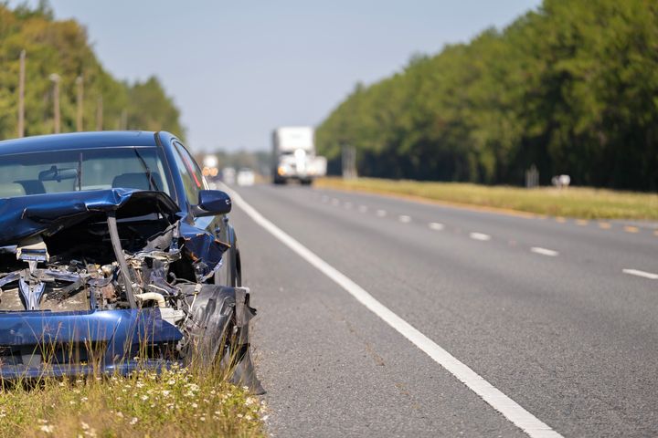 Auto onnettomuuden jälkeen maantien reunassa, keula vaurioitunut.