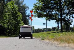 Pieni itsenäinen robottiajoneuvo ajaa kevyen liikenteen väylällä.
