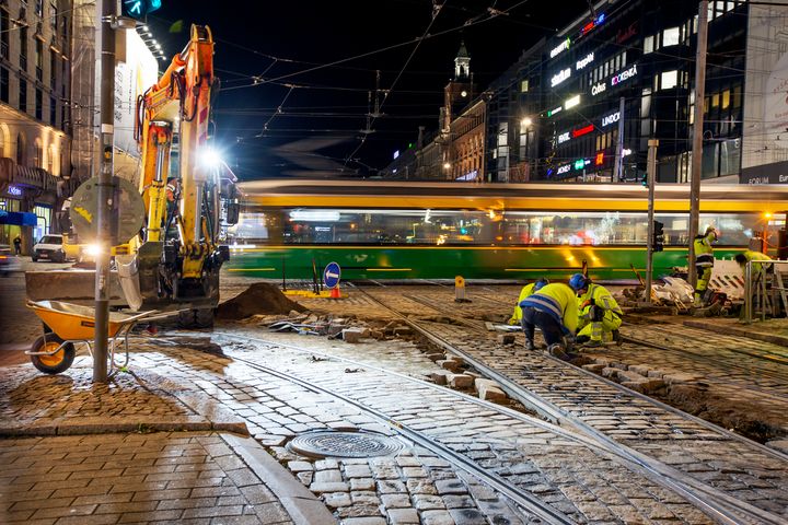 Raitiovaunu ylittämässä Mannerheimintietä, etualalla työntekijöitä korjaamassa kadun kivetystä