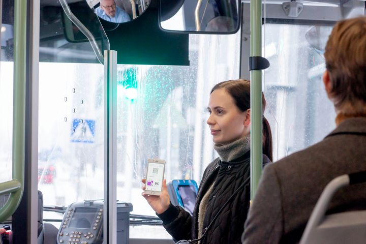Matkustaja näyttää matkapuhelimestaan HSL:n lippua linja-auton kuljettajalle