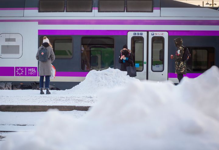 Juna asemalaiturilla, ihmisiä seisomassa junan edustalla
