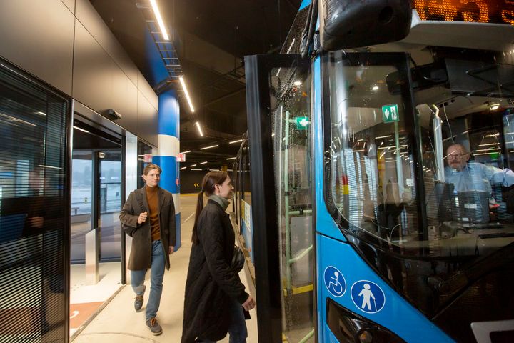 Kaksi matkustajaa nousemassa bussin kyytiin bussiterminaalissa