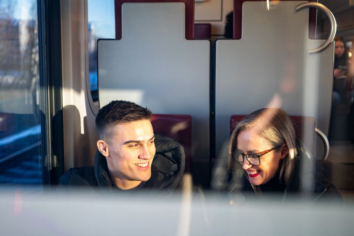 Kuvassa on kaksi henkilöä, jotka istuvat junassa.