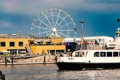 Suomenlinnan lautta, linja 19, Kauppatorilta kuvattuna, taustalla näkyy Allas Sea Pool ja maailmanpyörä, sininen kesätaivas