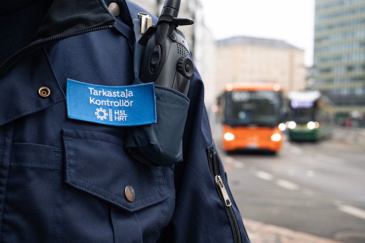 HSL:n matkalipuntarkastajan merkki ja taustalla bussi