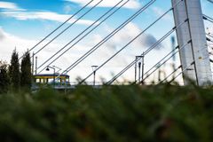 Raitiovaunu sillalla kuvattuna kaukaa, etualalla pensasta