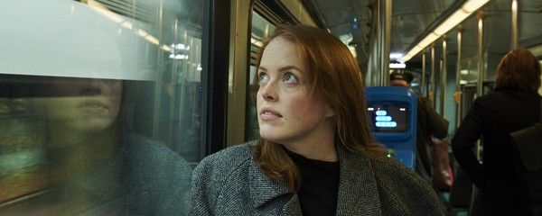 Bussimatkustaja katsoo ikkunasta ulos. Lasiin heijastuu hänen peilikuvansa.