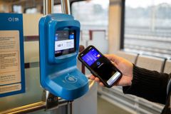 Matkustaja junassa näyttää puhelimeltaan maksukorttia lukijalaitteelle kertalipun ostamiseksi.