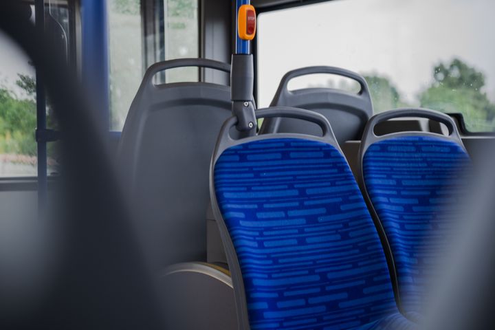 Tyhjiä sinisiä istuimia bussin sisällä.