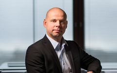 Leo Niemelä, S-Pankki. Mies istuu puvussa edessä olevassa huoneessa sälekahtimien edessä.