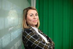 Annemari Airaksinen, S-Pankki, nainen seisoo selkä vihreää verhoa vasten ja hymyilee kameralle.