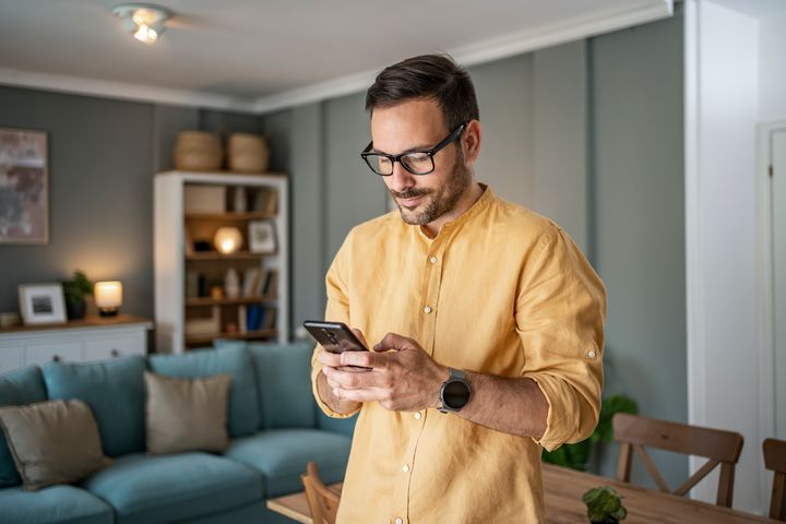Nuori mies katsoo puhelinta olohuoneessa.