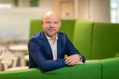 Tietoturvajohtaja Leo Niemelä, S-Pankki. Kuvassa on mies, jolla on sininen puku. Hän nojaa vihreään sohvaan.