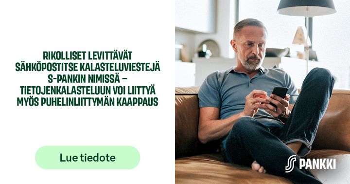 Henkilö käyttää älypuhelinta kotinsa olohuoneessa istuen sohvalla