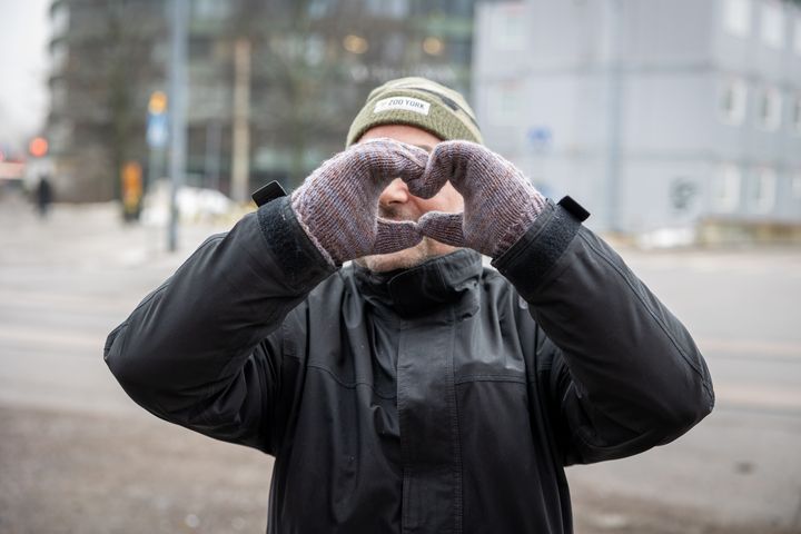 Henkilö tekee lapasilla sydämen muotoista elettä keskustassa.
