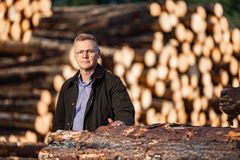 Matti Kylävainio seisomassa puupinojen edessä