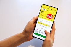 Henkilö pitää älypuhelinta, jossa on auki lotto-sovellus.