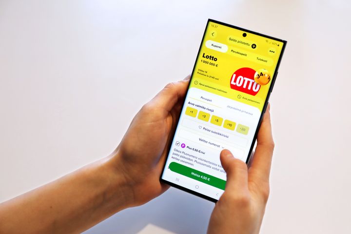 Henkilö pitää älypuhelinta, jossa on auki lotto-sovellus.
