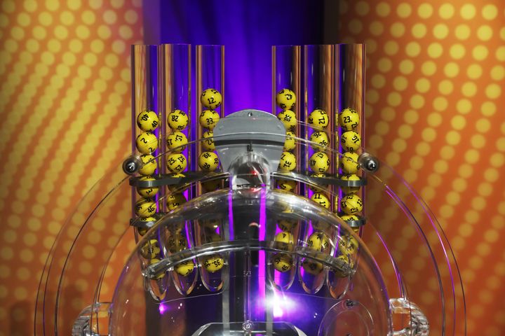 Lottokone täynnä keltaisia lottopalloja, joissa on mustia numeroita.