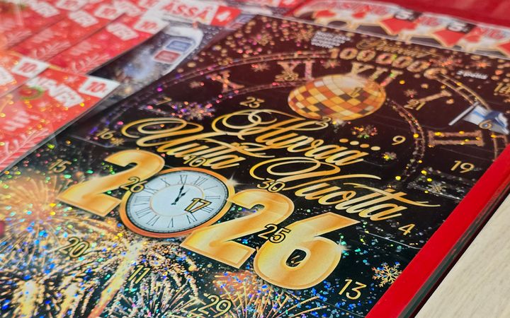 Kalenteriarpa, jossa on teksti "Hyvää Uutta Vuotta 2026" ja kellon kuva.