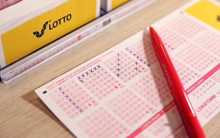 Punainen kynä lepää täytetyn lottokupongin päällä.