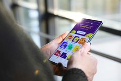 Henkilö pitää kädessään älypuhelinta, jonka näytöllä on rahapelikuvakkeita ja palkintosummia.