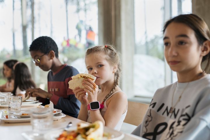 Oppilaat ruokailemassa ruokapöydän äärellä.