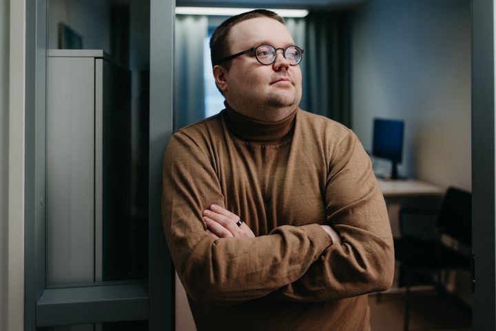 Antti Eteläaho katsoo oikealle kädet edessä ristissä, kuva rajattu noin vyörätön korkeudelta, taustalla toimistohuone