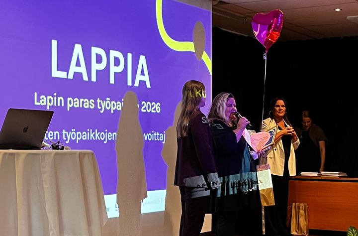 Kuvassa palkinnonjakotilaisuus, jossa nainen vastaanottaa palkinnon Lappian puolesta.