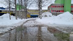 Sulamisvettä ja lumikinoksia rakennuksen edessä.