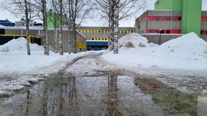 Sulamisvettä ja lumikinoksia rakennuksen edessä.