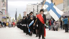 Promootiokulkue kulkemassa Oulun rotuaarilla. Edessä liehuu Suomen lippu.