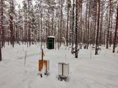 Talvinen metsämaisema, jossa on oranssi laatikko ja luminen koeala. Oikealla puolella lumikasa vertailua varten.