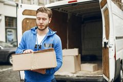 mies kantaa laatikkoa pakettiautosta