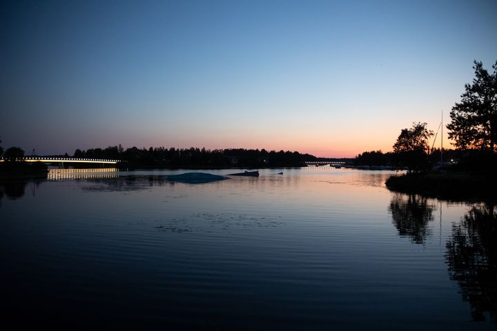 Hämärtyvä ilta Pikisaaressa, siluetteja ja heijastuksia vedessä.