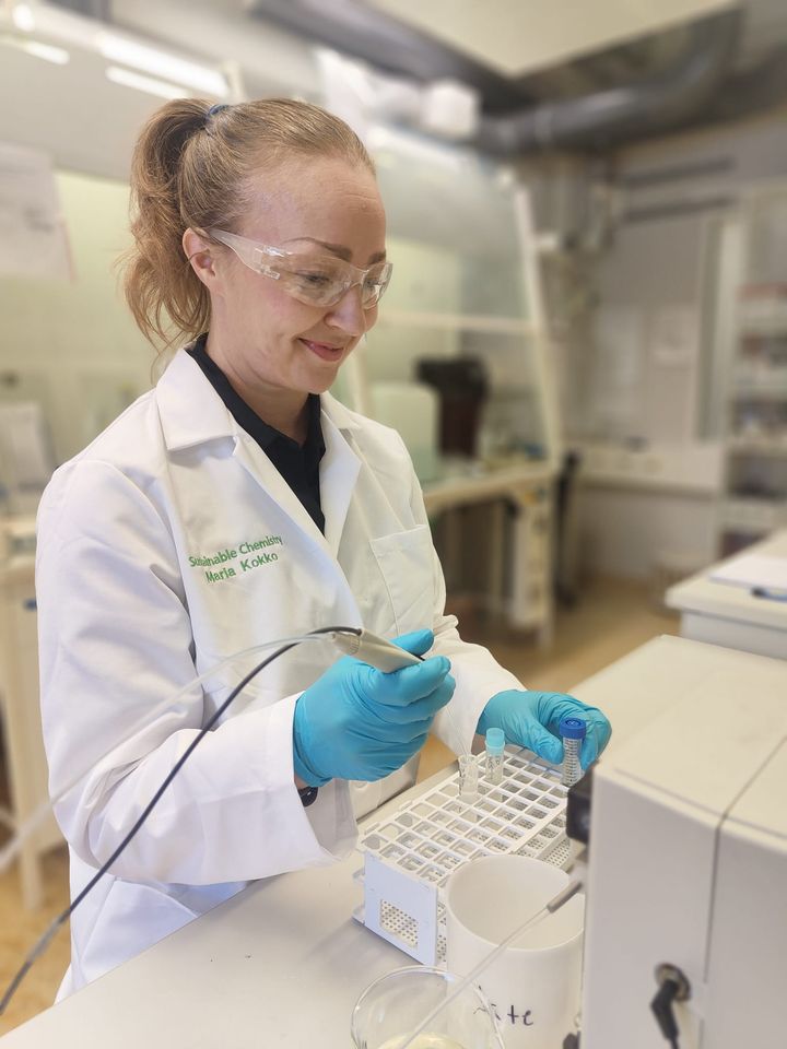 Tutkija laboratoriossa valkoisessa takissa ja suojalasit päässä.