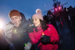 Kaksi henkilöä puhaltaa saippuakuplia ulkona talviasusteissaan iloisella ilmeellä.