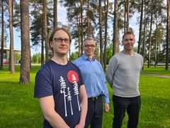 Kolme henkilöä seisoo vierekkäin Oulun yliopiston puistomaisessa ympäristössä.