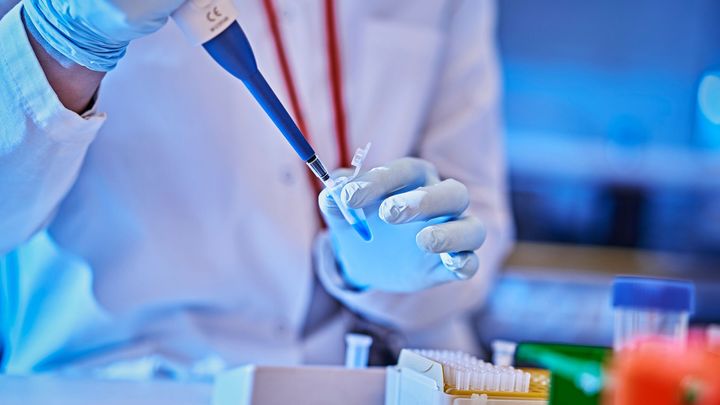 Henkilö käyttää pipettiä laboratoriossa.