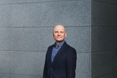 Kuva Pekka Rossista harmaan seinän edessä.